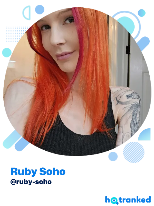 Woman with long bright red hair and tattoos wearing a black top, Ruby Soho